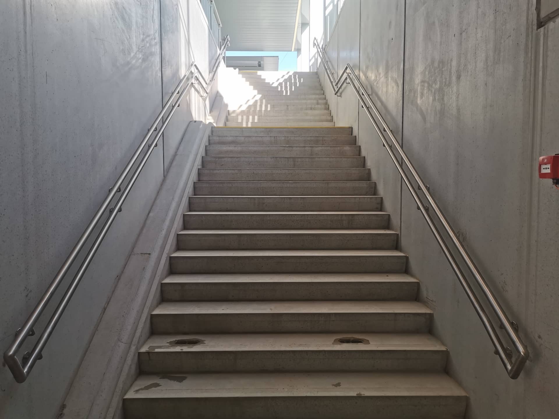 Escalier en béton avec rampes métalliques.